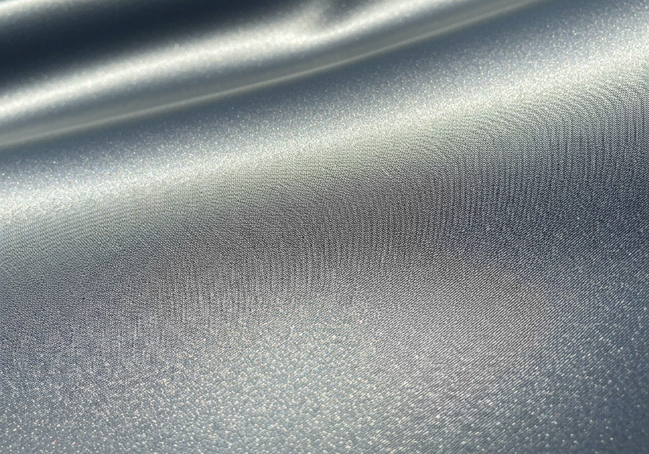 detal gładkiej tkaniny poliestrowej z widoczną fakturą i delikatnym odbiciem światła w naturalnym świetle